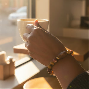 Close-up of a wrist wearing a jasper beaded bracelet on a neutral background