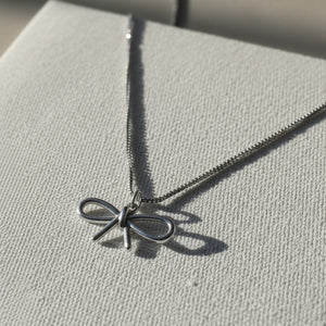 Gold necklace with a bow pendant on a beige fabric background