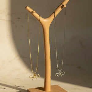 Gold and Stainless steal necklace with a butterfly pendant on a white surface