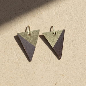 Pair of triangle-shaped brown leather earrings with gold color scheme on a white background