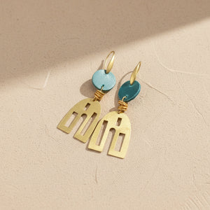 A pair of abstract leather and brass earrings with a polished brass base and turquoise upcycled leather attachments.