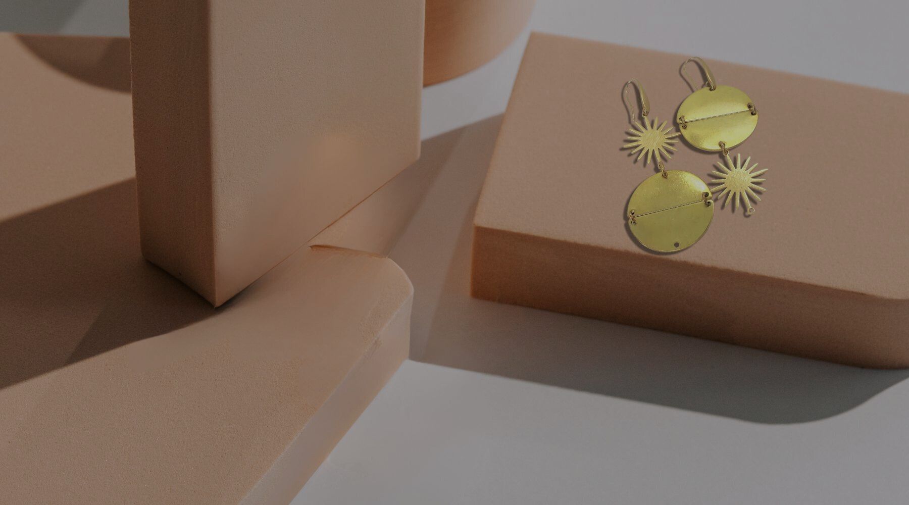 Gold-plated twin eclipse earrings sitting atop a box.
