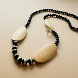 Necklace with black beads and wooden pendants on a beige background