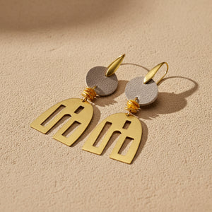 Gold and gray leather earrings on a beige background
