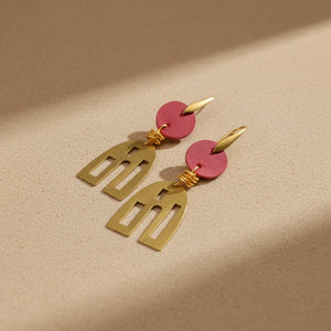 Gold and red earrings on a tan background