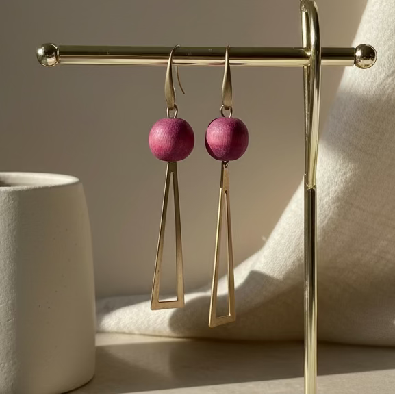 Pink earrings on a stand with a blurred indoor background