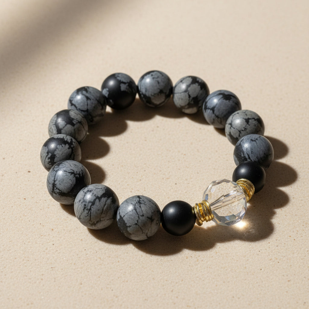Snowflack Obsidian beaded bracelet with a clear crystal bead on a light gray background
