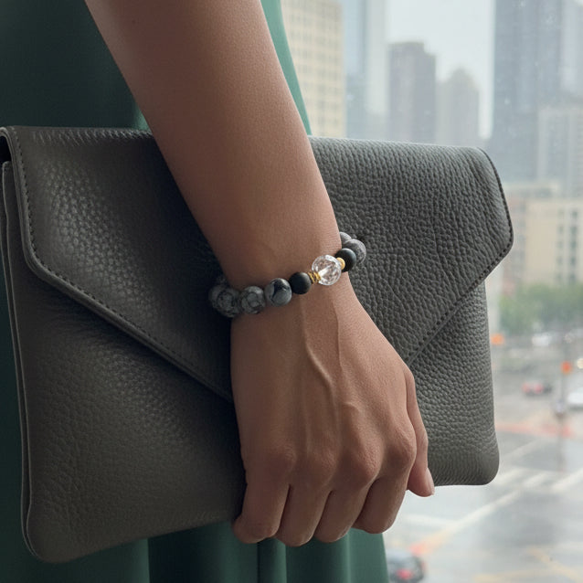 Snowflack Obsidian beaded bracelet with a clear crystal bead on a light gray background