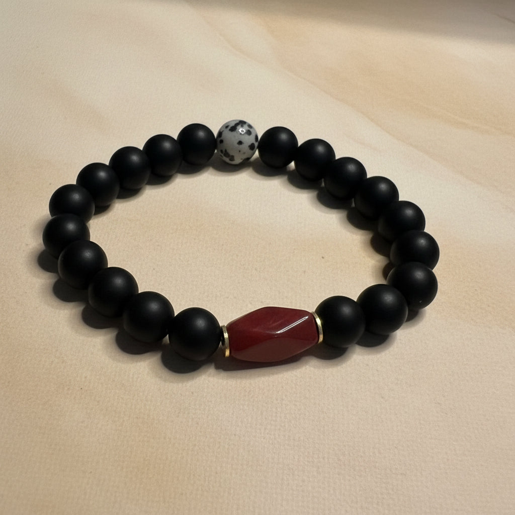 Black beaded bracelet with a red stone bead on a white background