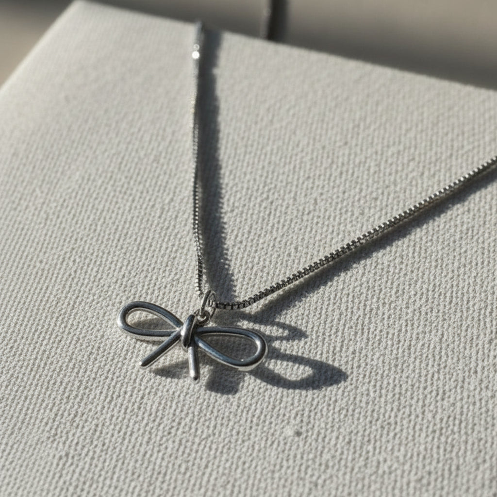 Gold necklace with a bow pendant on a beige fabric background