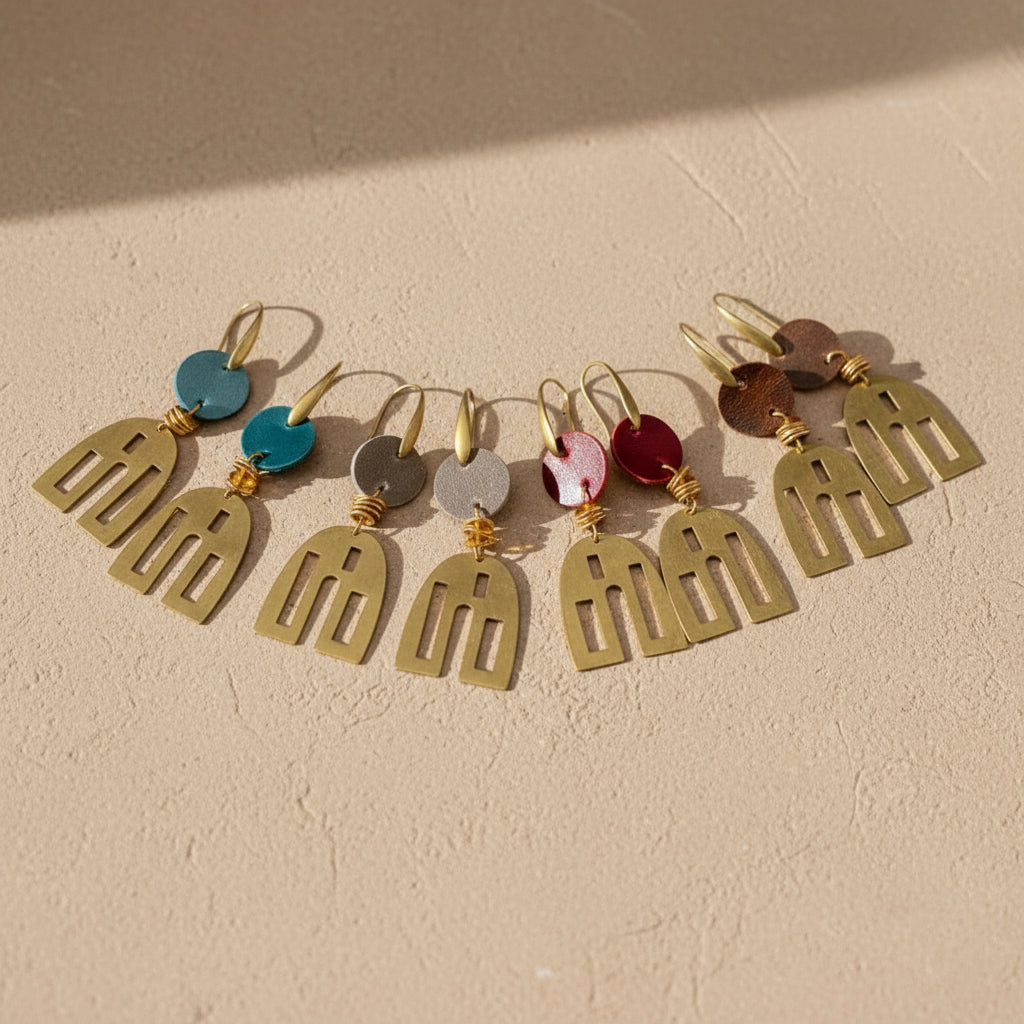 Gold  earrings with colorful  leather accents on a tan background